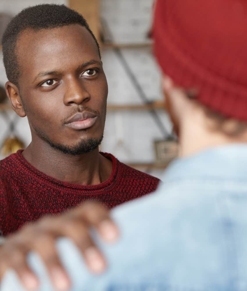 supportive friend holds man's shoulder 