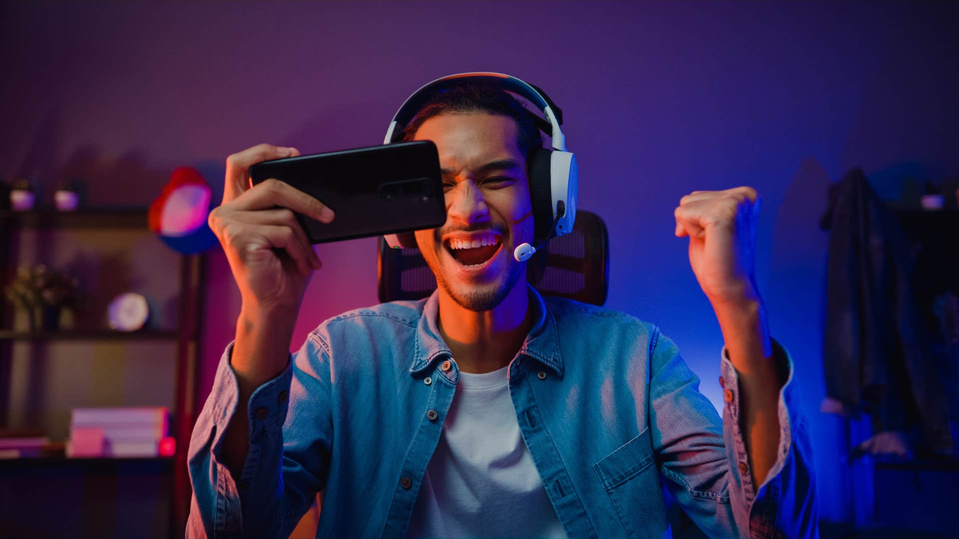 man wearing headphones cheering and playing game on phone
