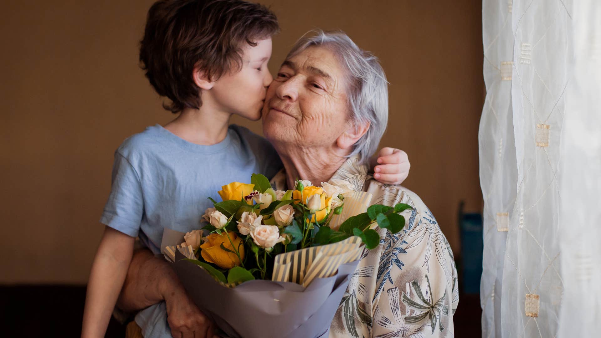 little boy who learned manners and social etiquette kissing his grandmother