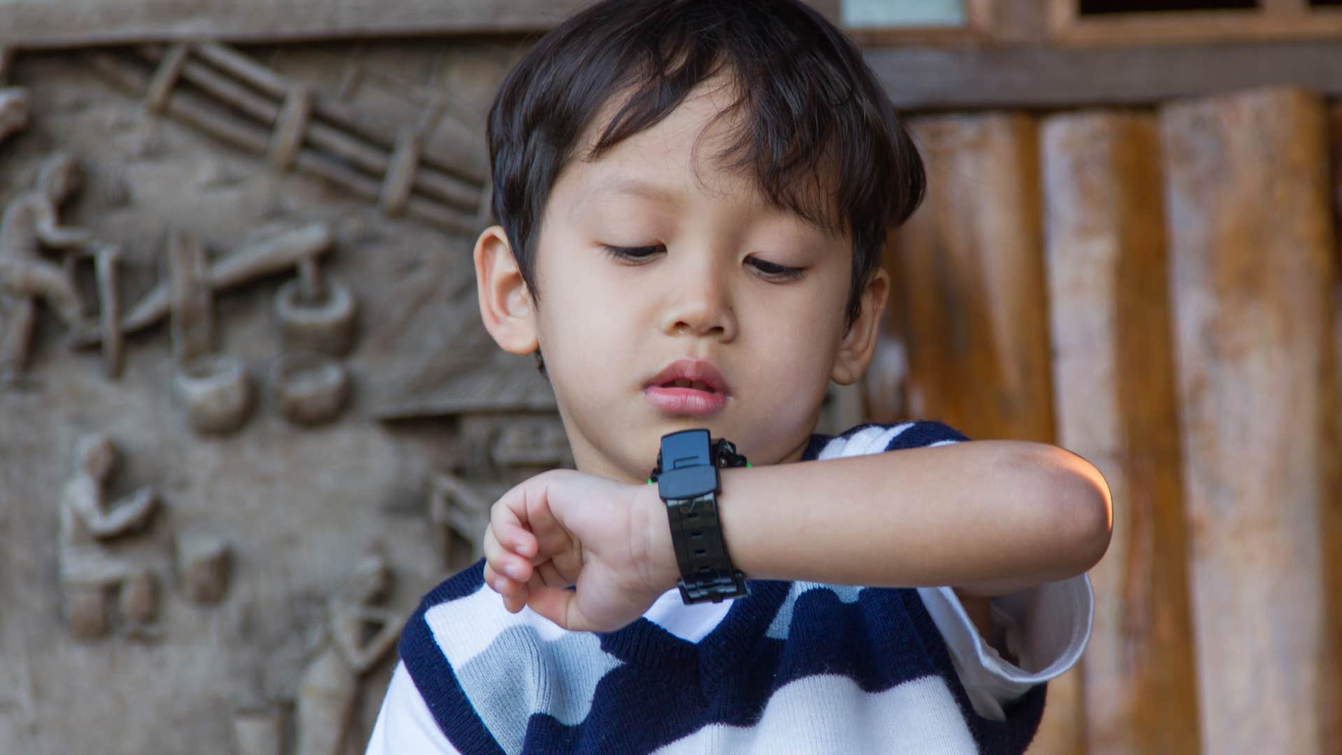 little boy learning to be punctual while looking at his watch