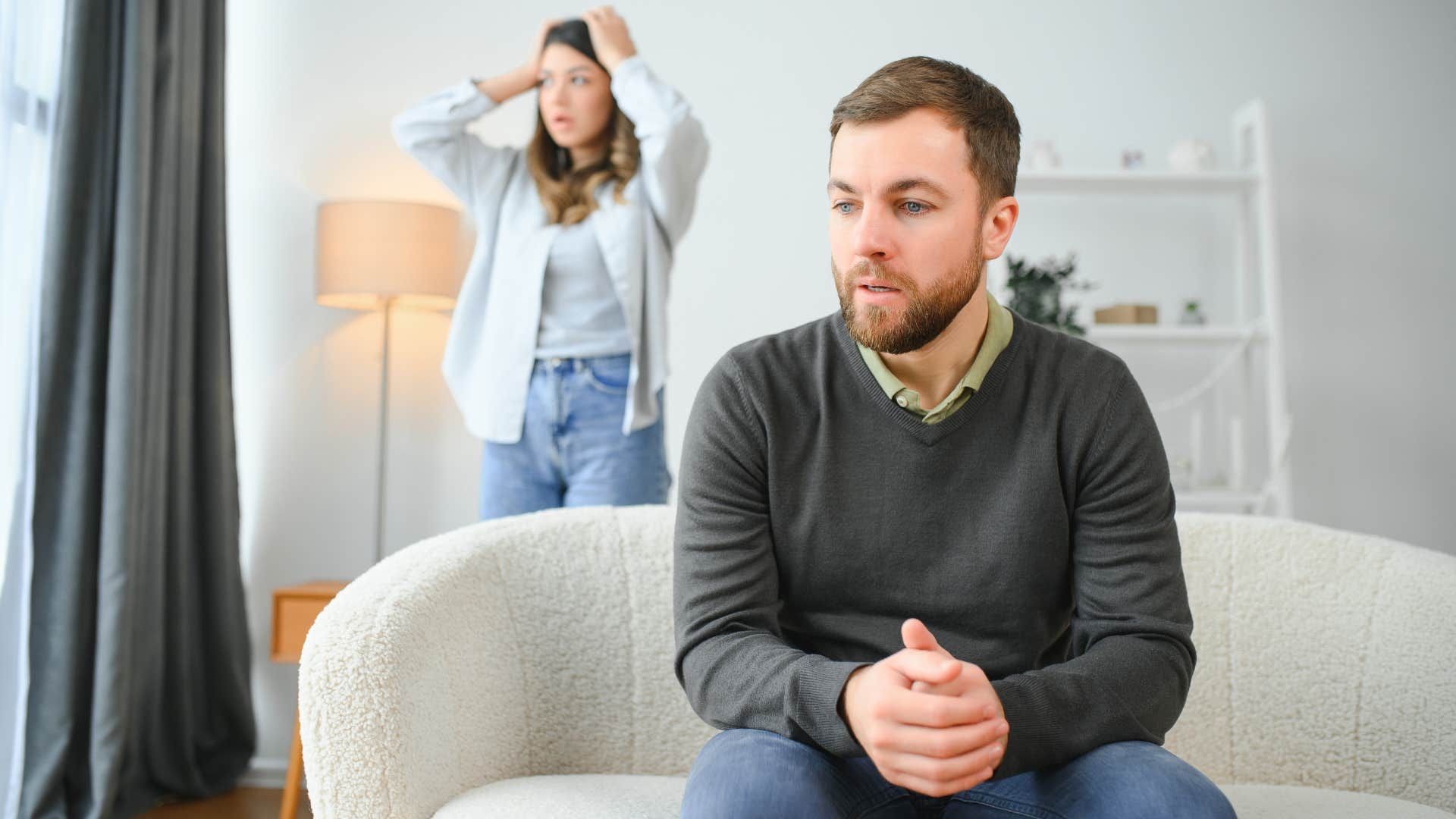 upset woman standing behind man who is avoiding her apology