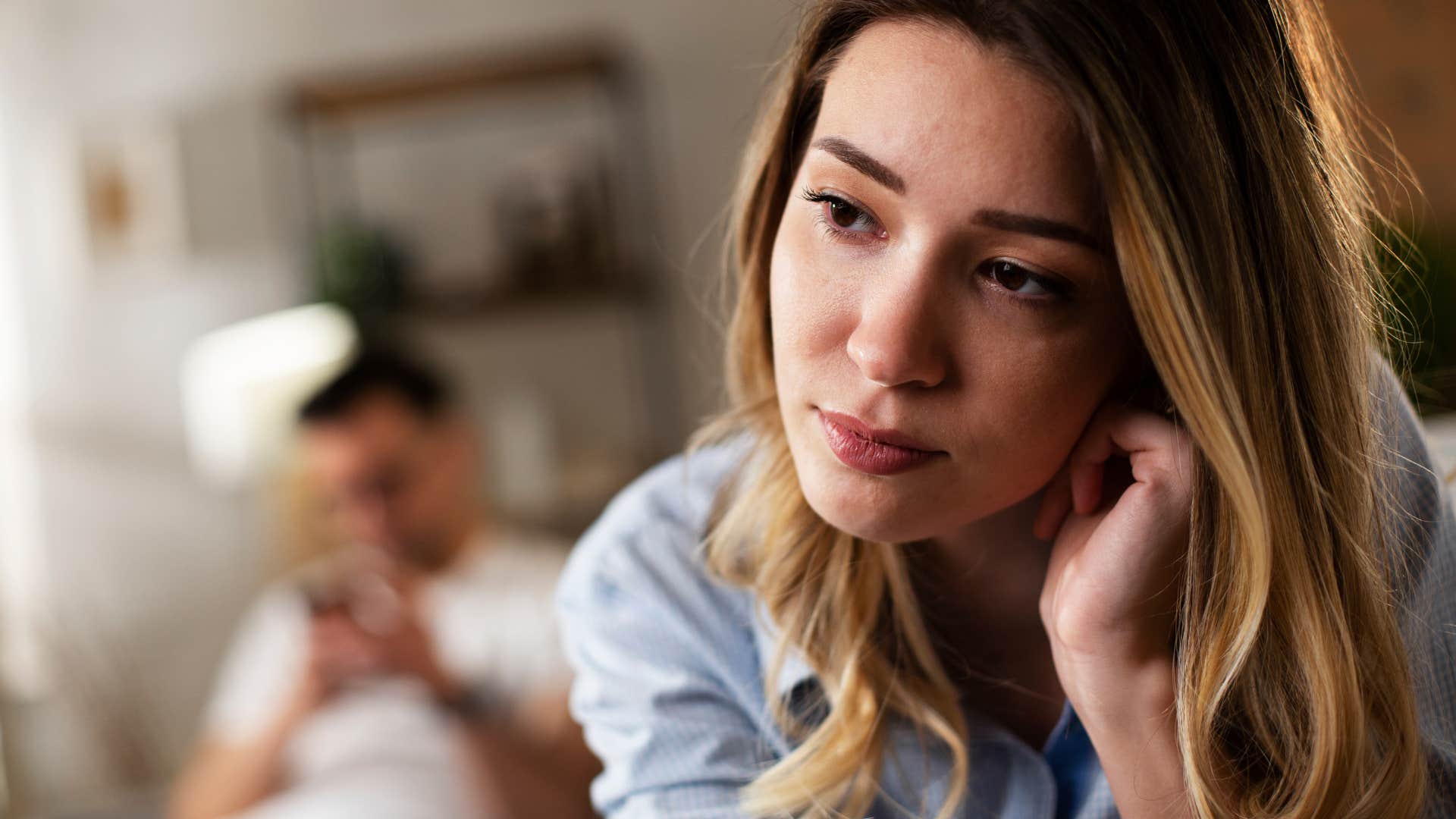 upset lonely woman sitting away from man tolerating his emotional unavailability