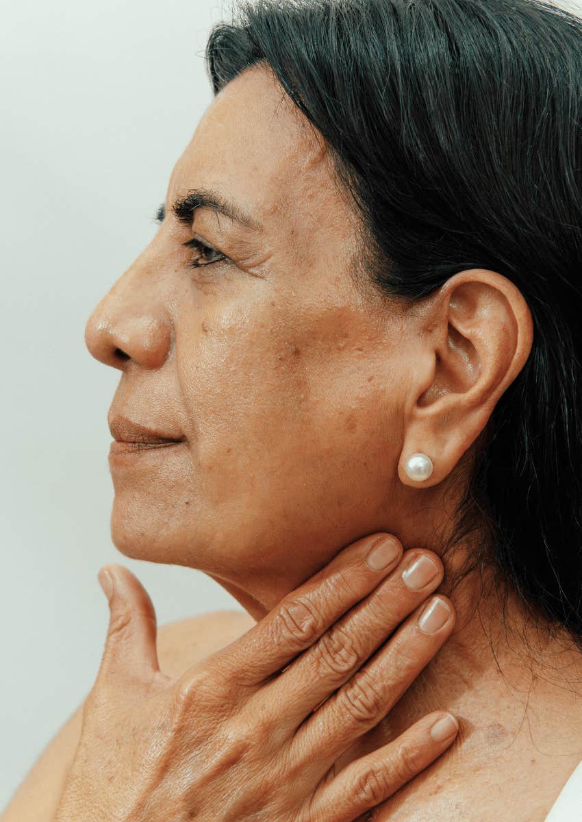 mature woman applying skincare to her chin and neck