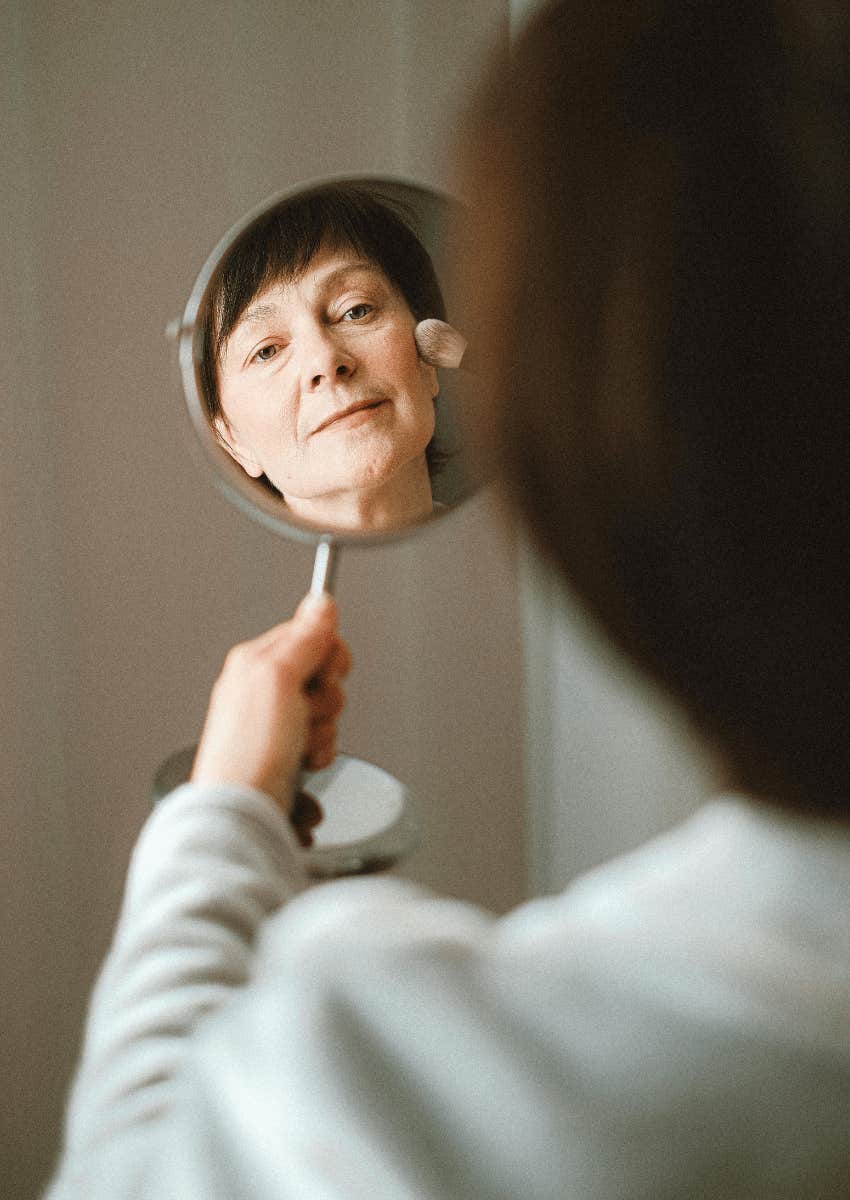 mature woman looking into mirror at her reflection