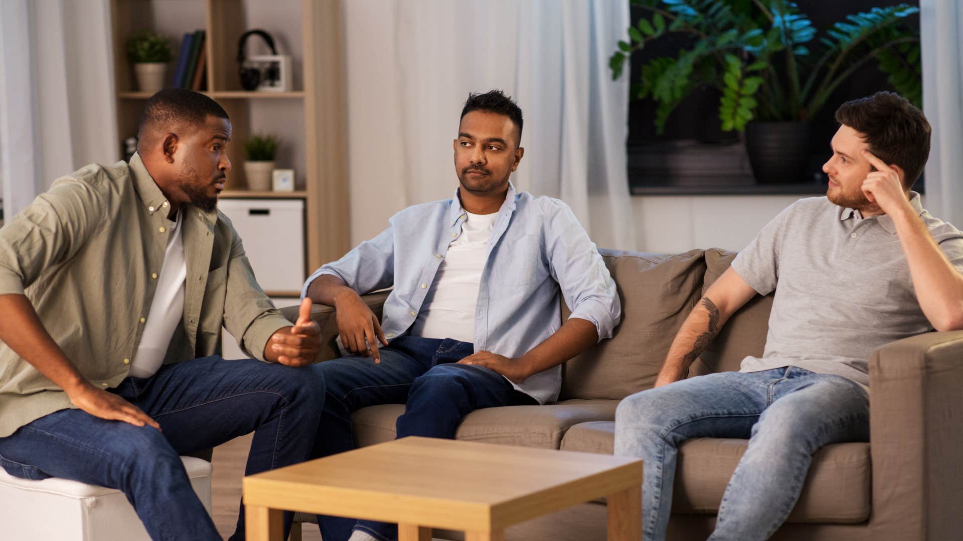 man defending his friend while talking to group of other men