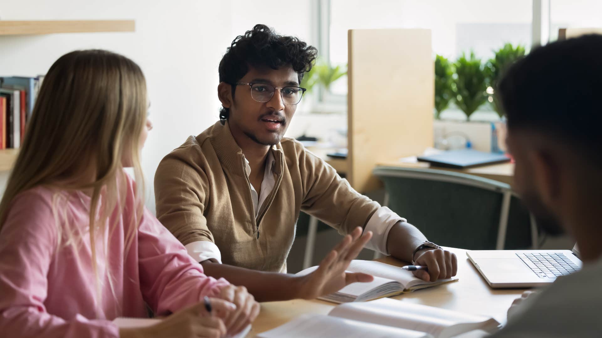 man in a business meeting telling colleagues to listen to female co-worker