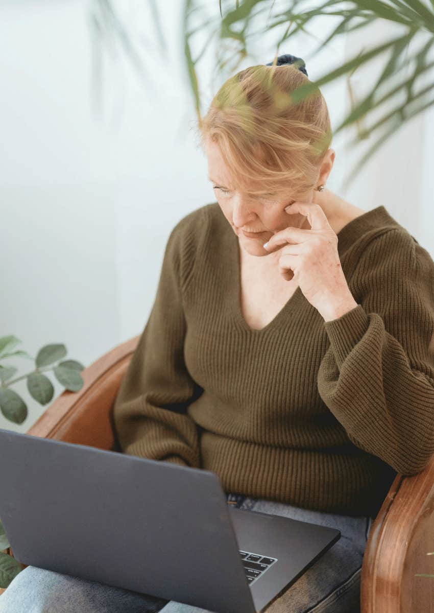middle aged woman focused on an open laptop