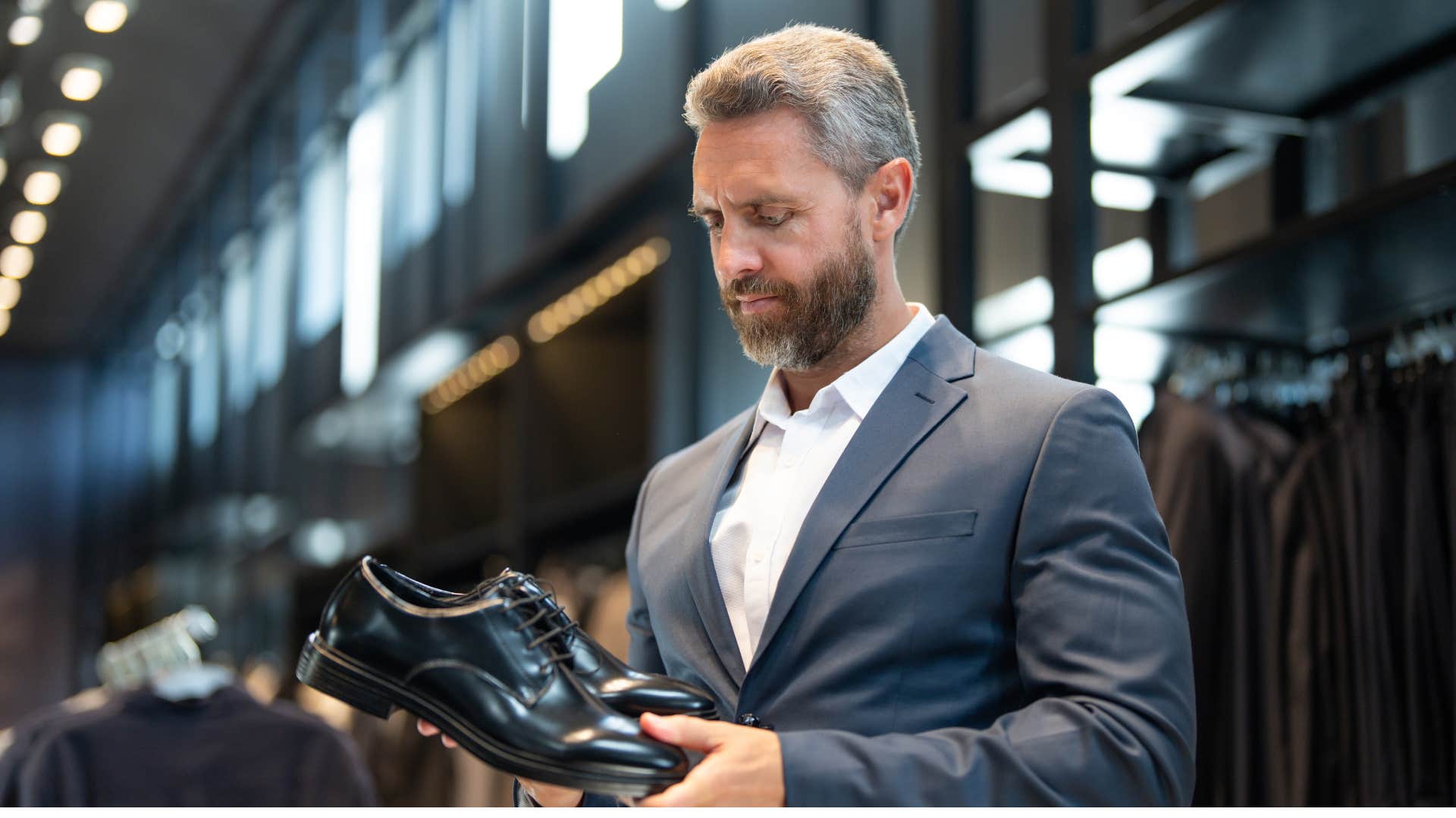 man in suit spending money to keep up with others as he stares at black shoes