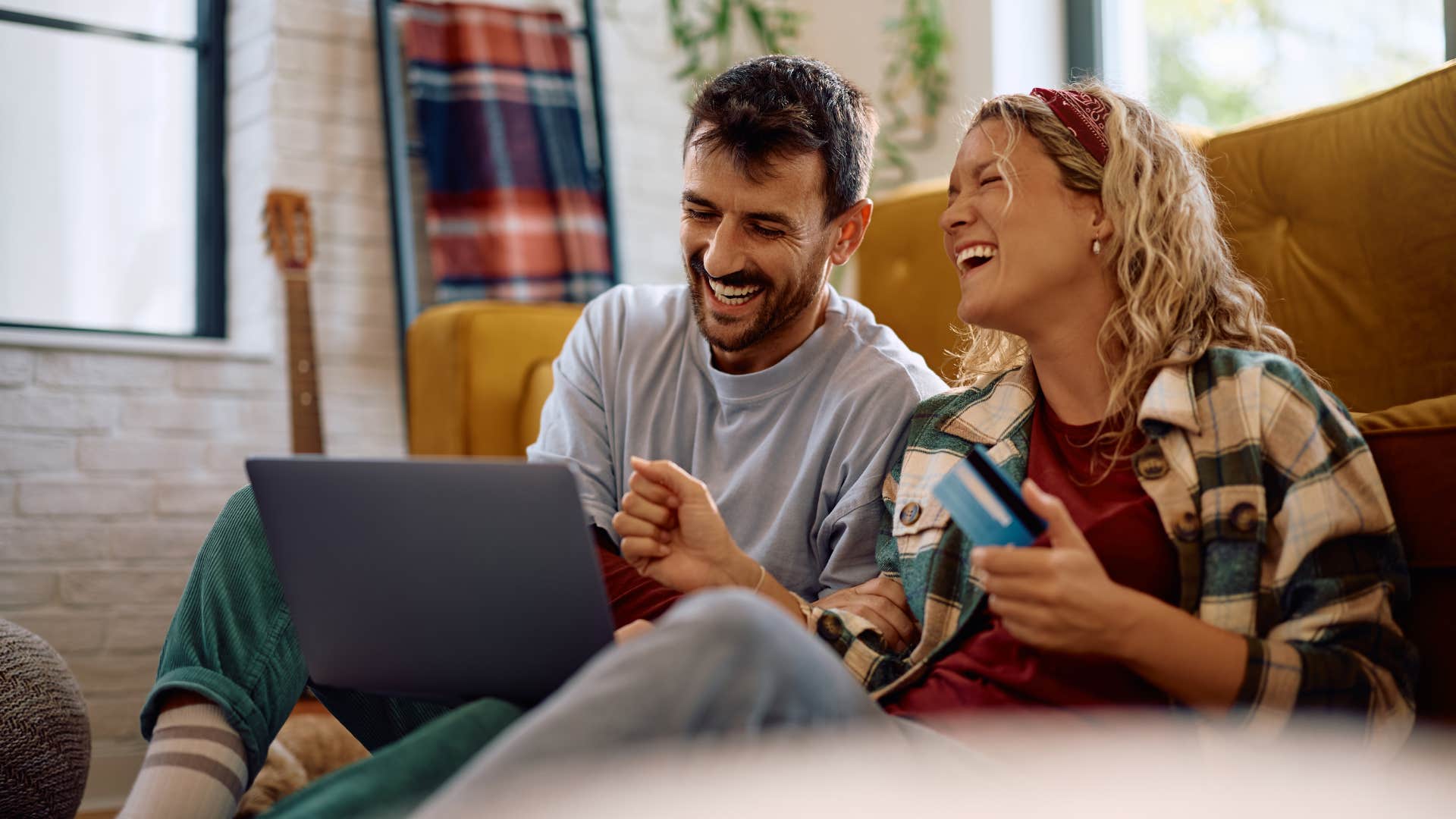 couple smiling brightly as they use credit cards for holidays