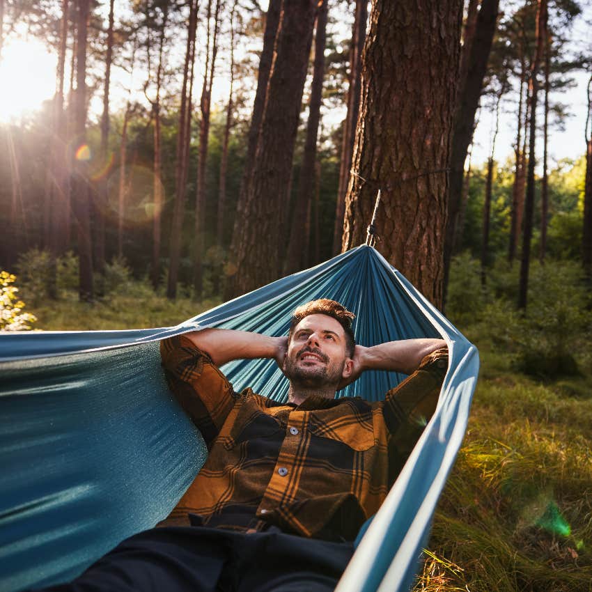 happy man lying in hammock in forest experiencing mindfulness