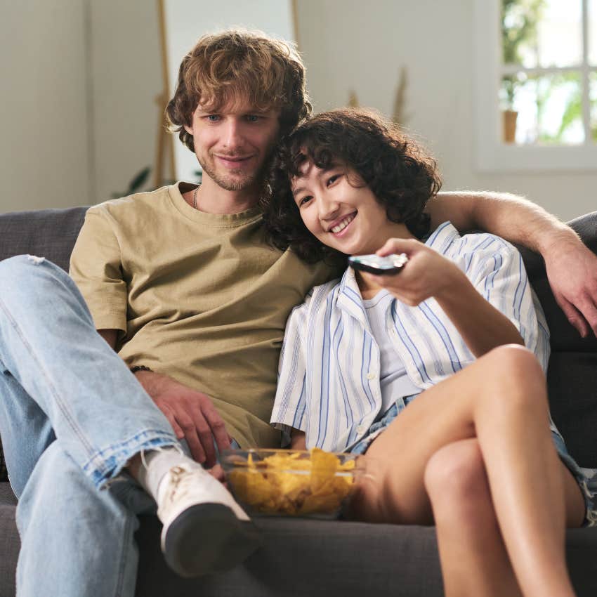young couple sitting on couch together watching tv