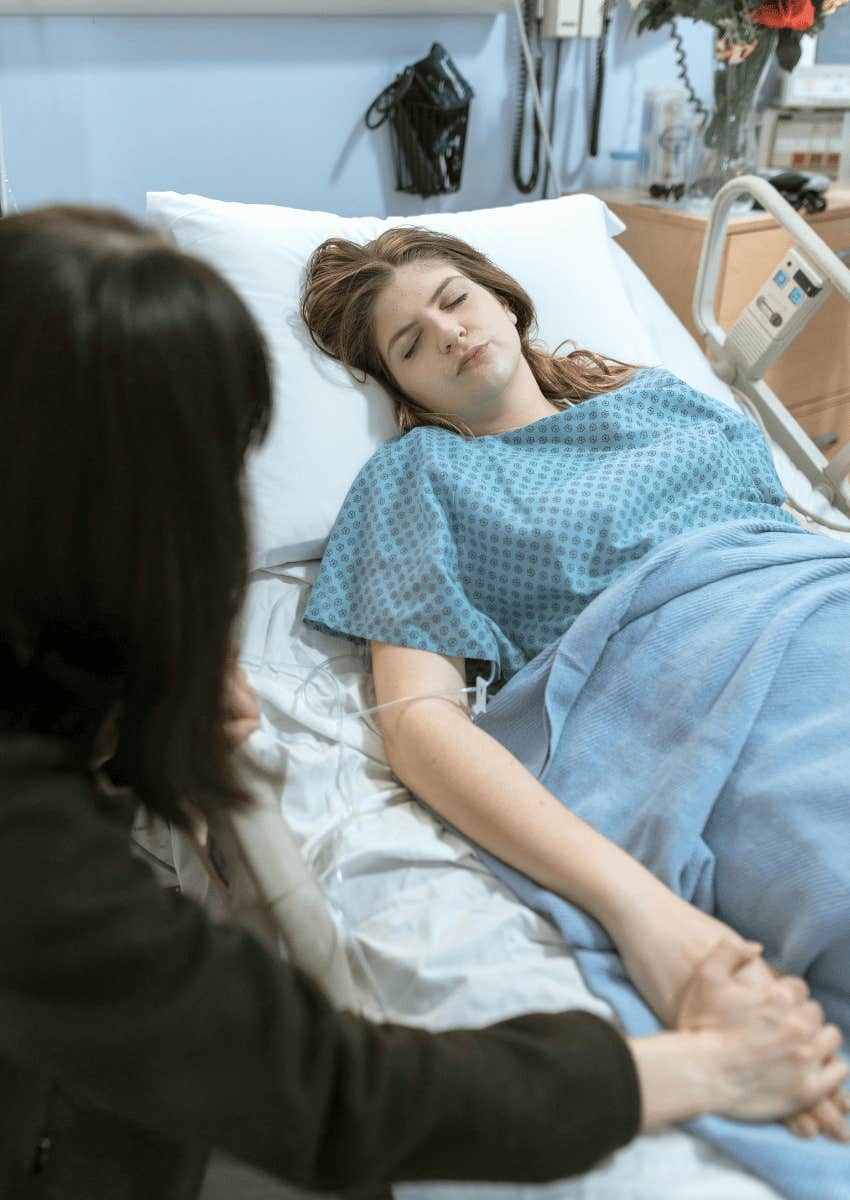 mother holding adult daughter's hand in hospital