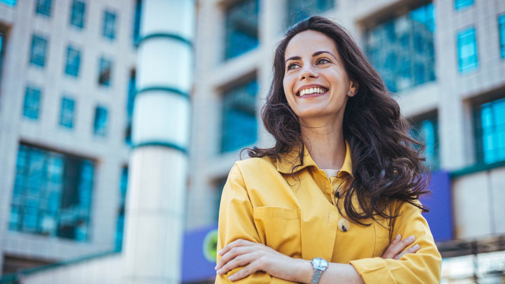 woman in yellow shirt crossing arms as she is feeling hopeful and confident