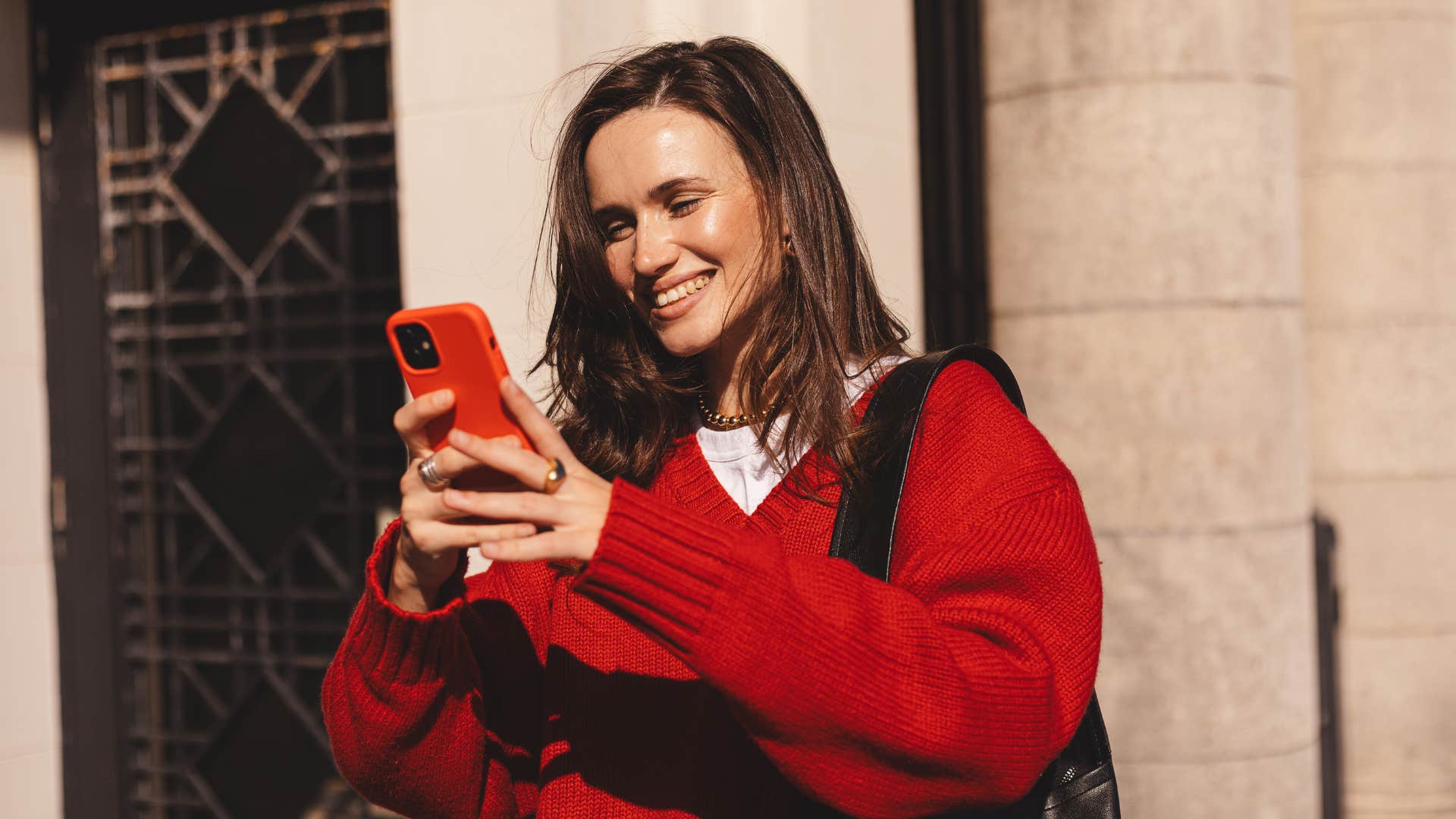 woman in red shirt talking to her parents anytime as she smiles brightly at phone