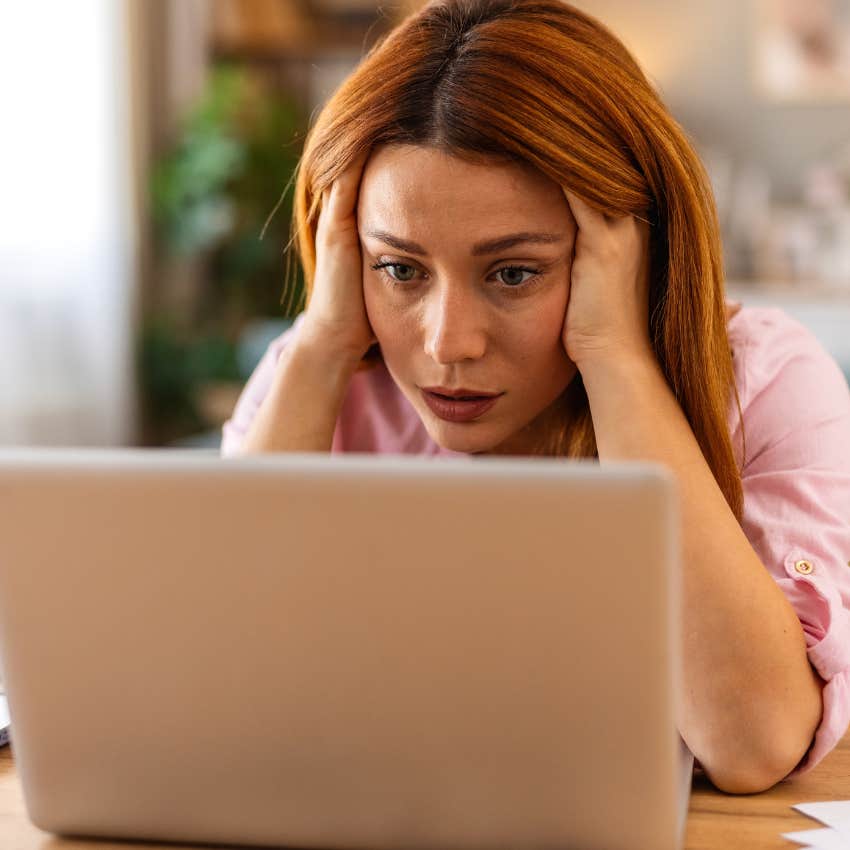 Woman making herself look dumb by slouching in a chair while looking at her laptop.