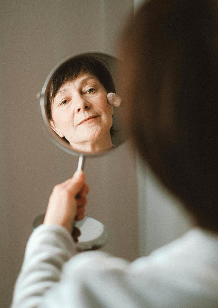 older woman looking in her mirror with a thoughtful expression
