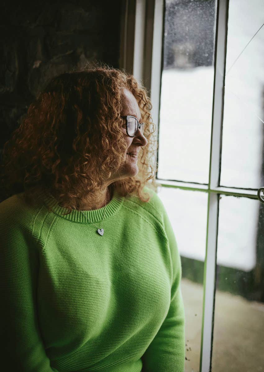 older woman looking out of window alone