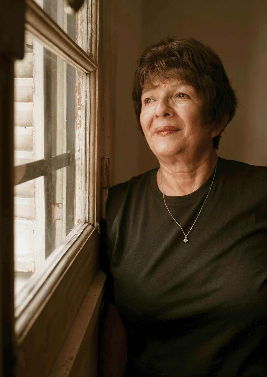 older woman looking out of window thoughtfully