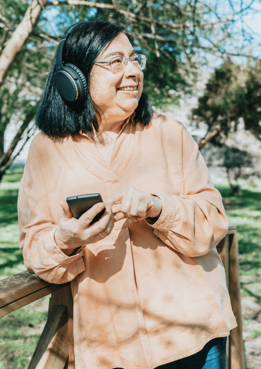 older woman wearing headphones outdoors