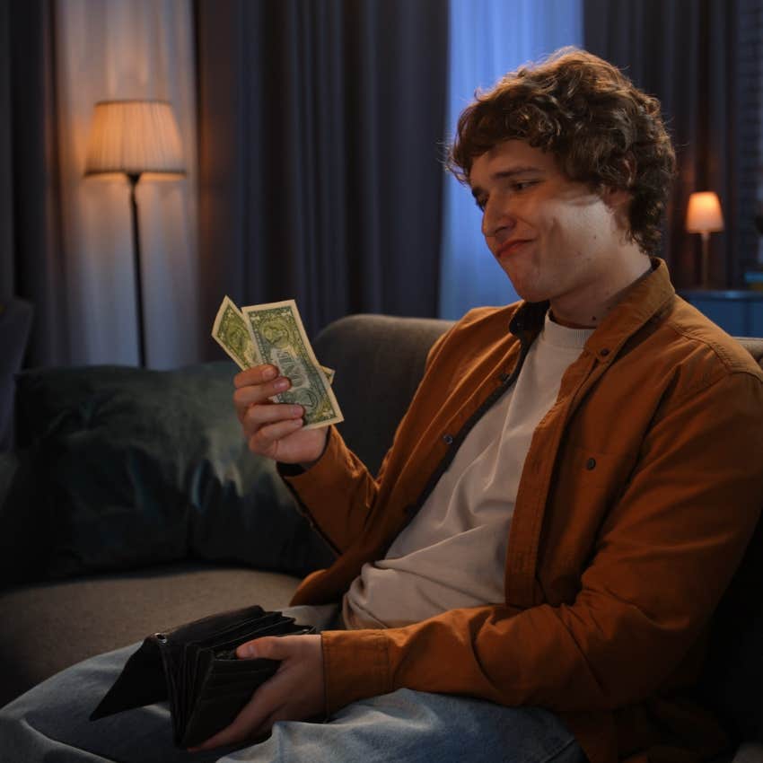 young man holding money sitting on couch