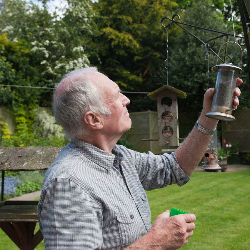 man refilling birdfeeders as part of his longevity fitness routine for his brain