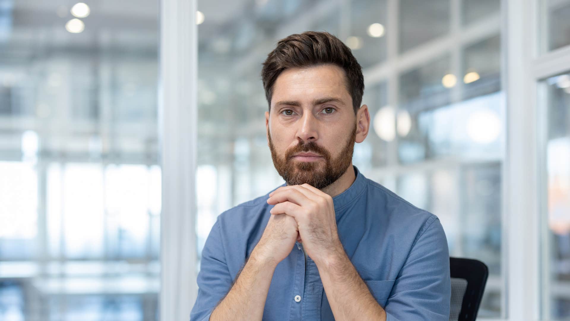 man in blue shirt thinking deeply at work as he's highly independent