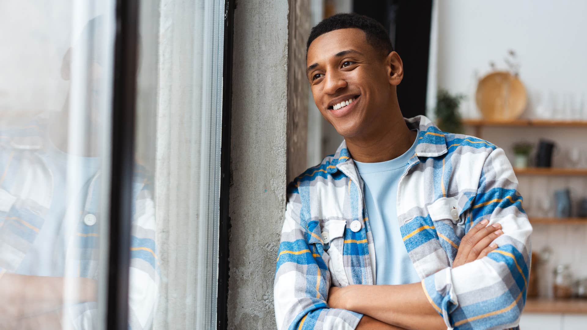man staring out window smiling as he's meaning focused