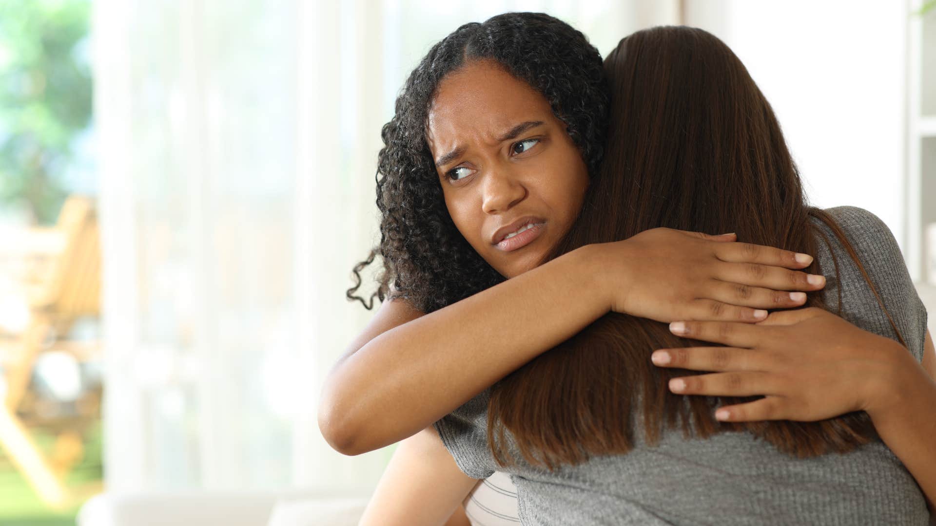 woman reluctantly hugging friend in social space