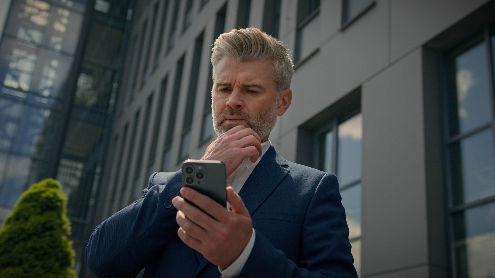 skeptical man looking at phone suspiciously 