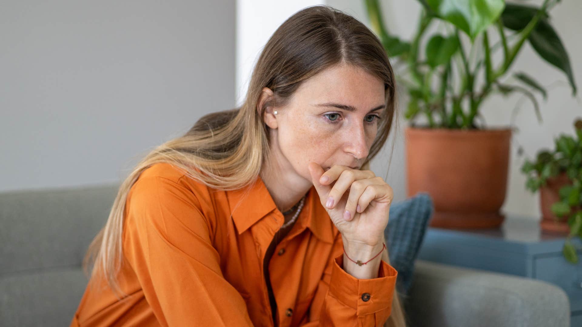 pensive woman without tattoos sitting at home