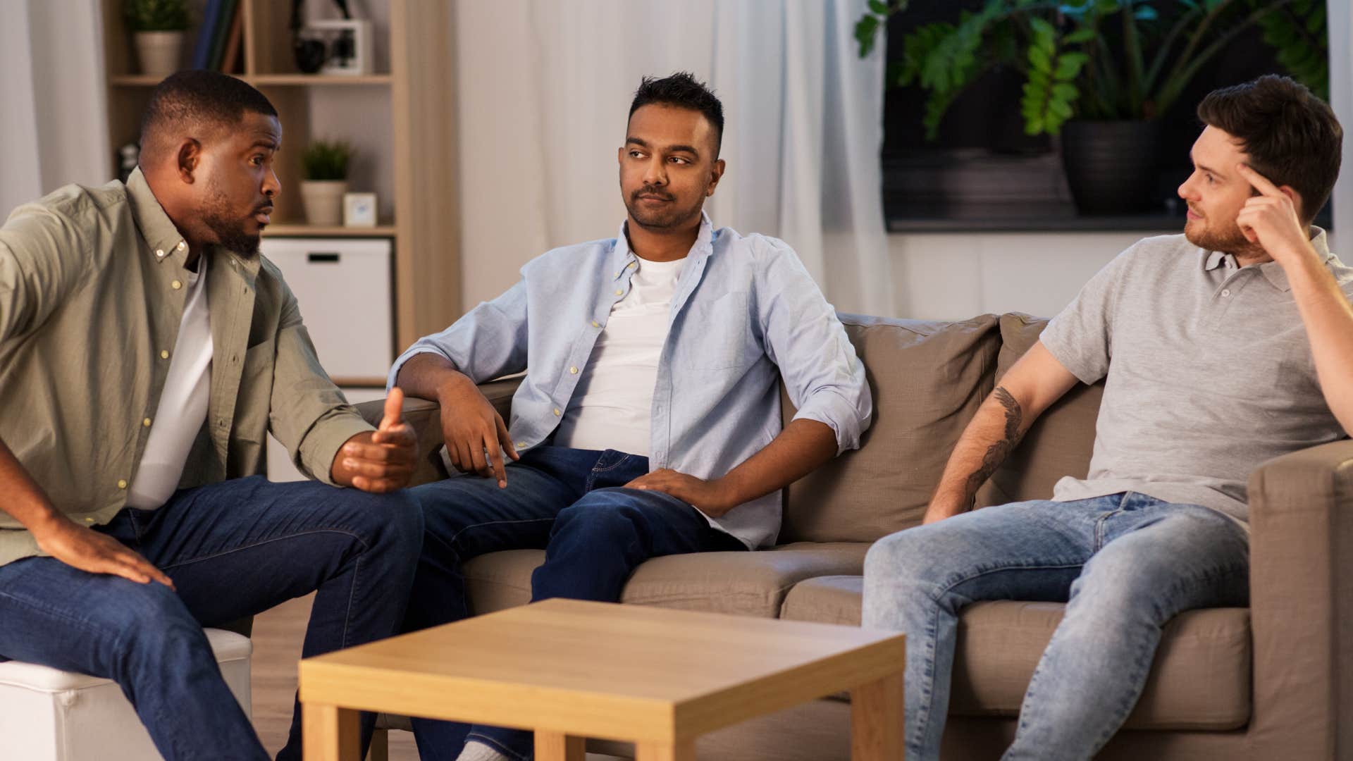 man sitting with friends in room feeling tense