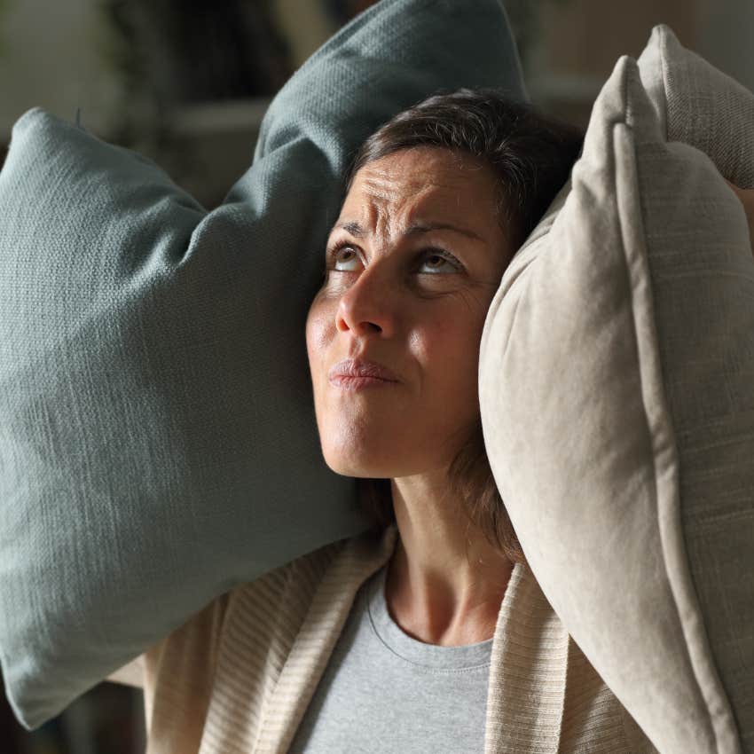 Woman who can't stand her neighbors covering her ears to deal with constant noise