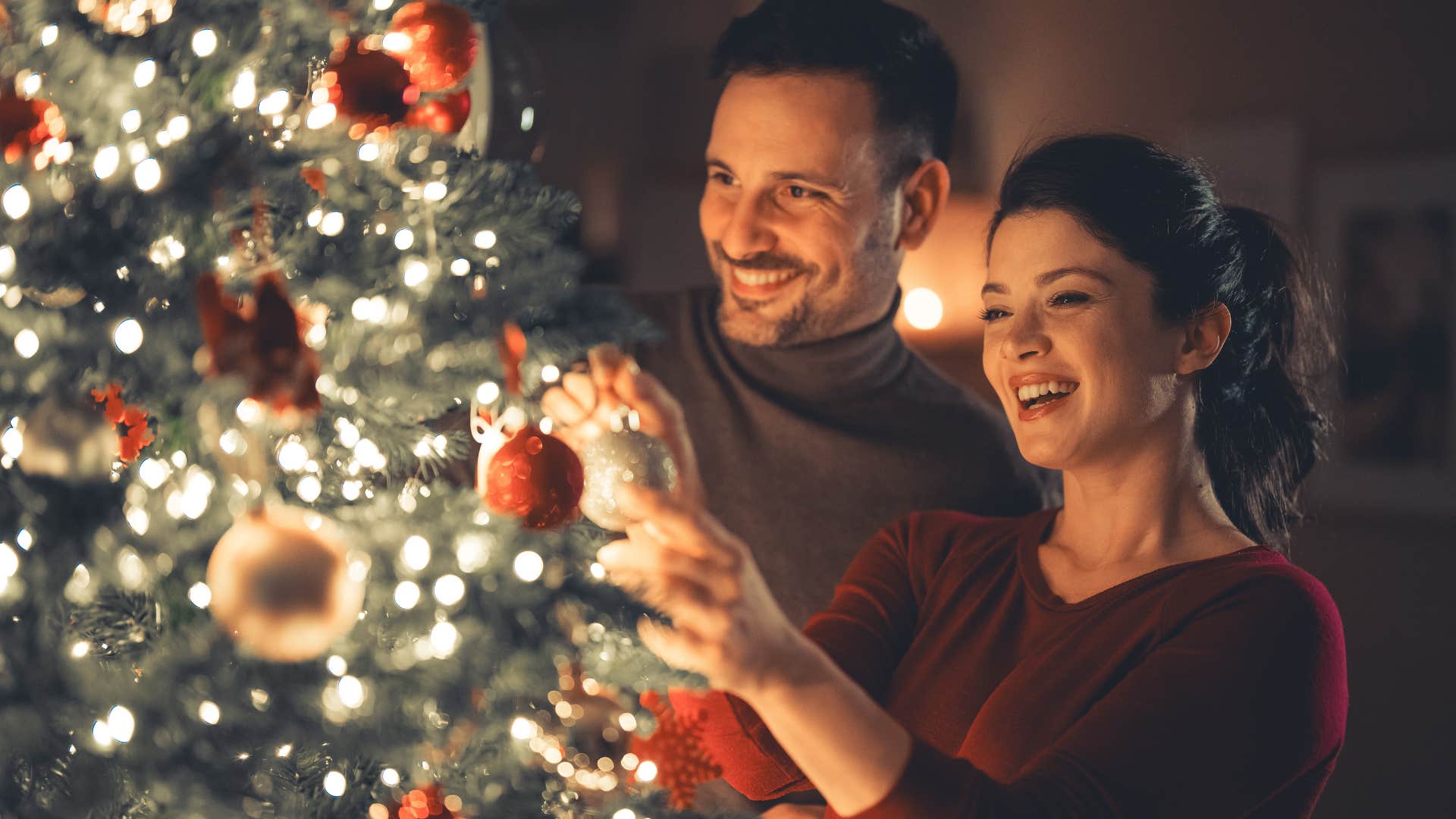 couple continuing family traditions putting up a Christmas tree