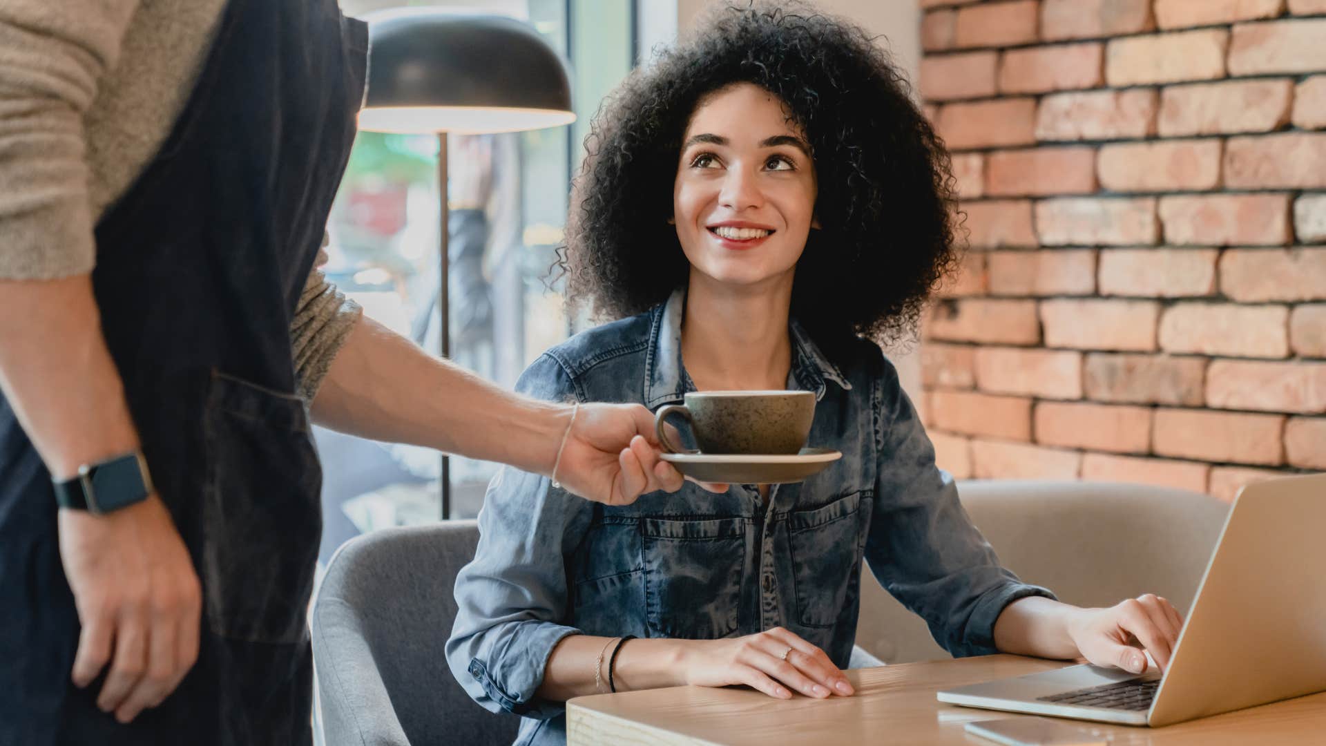 Woman who leads with their internal values smiling at a barista.