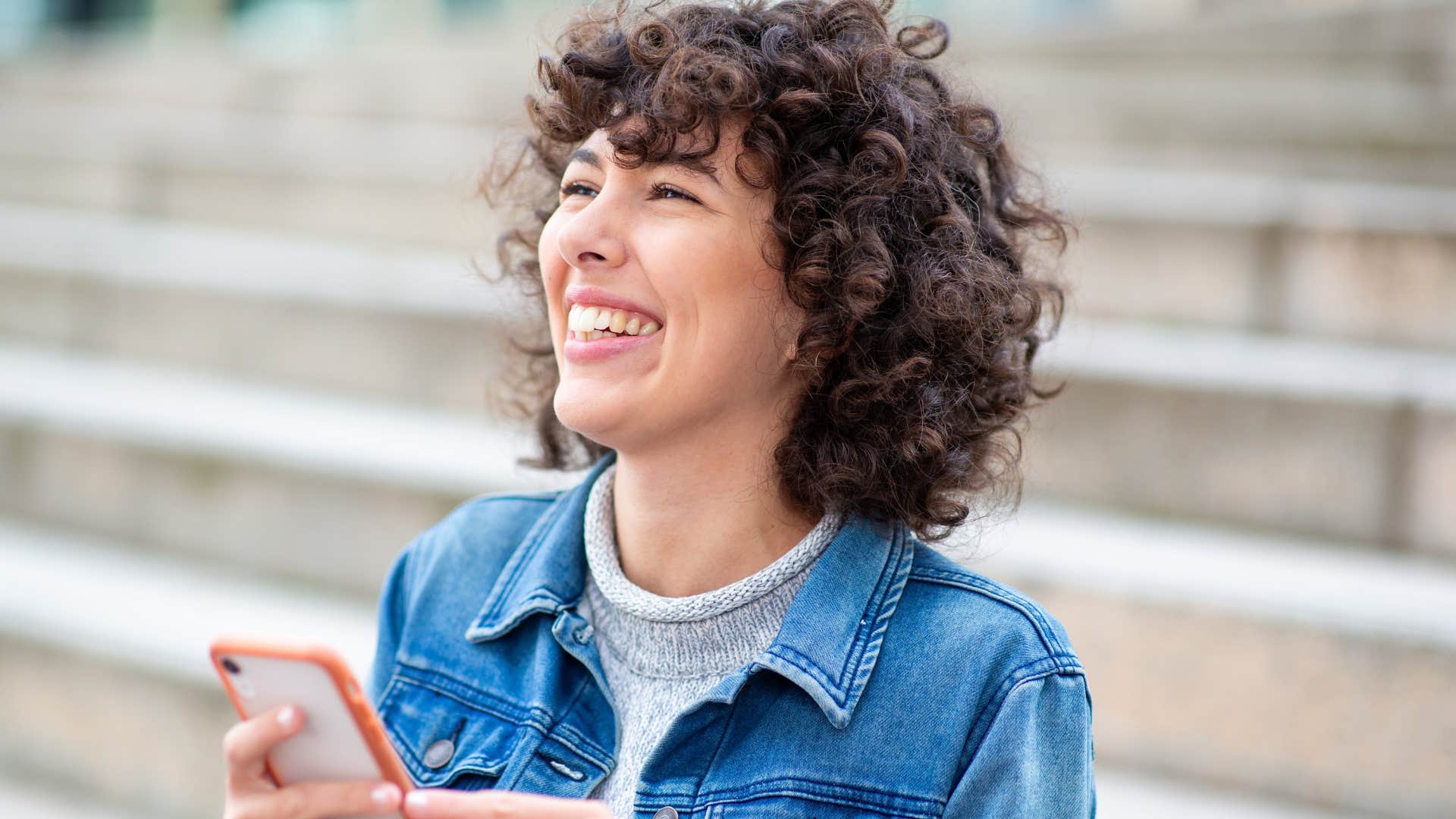 grounded and calm woman on her phone outside smiling