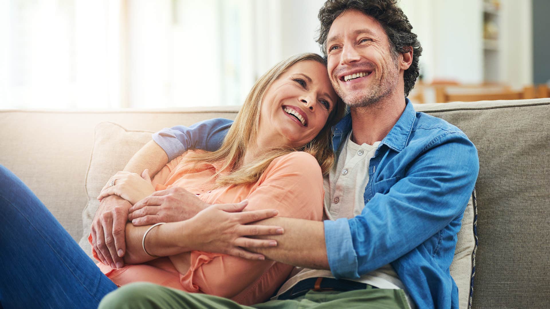 smiling couple cuddling on couch