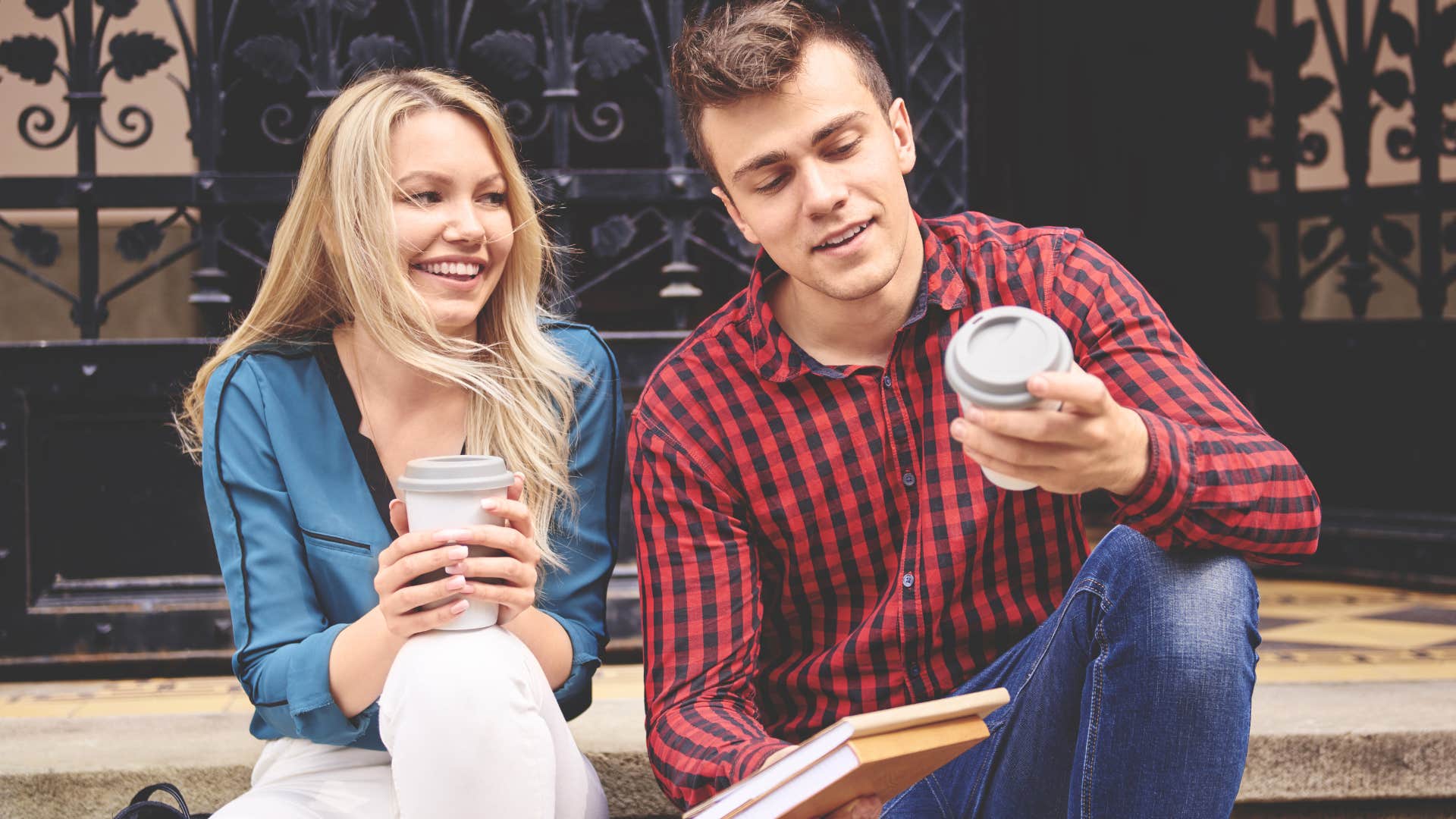 Man who is falling for a woman sits on a stoop with her drinking coffee