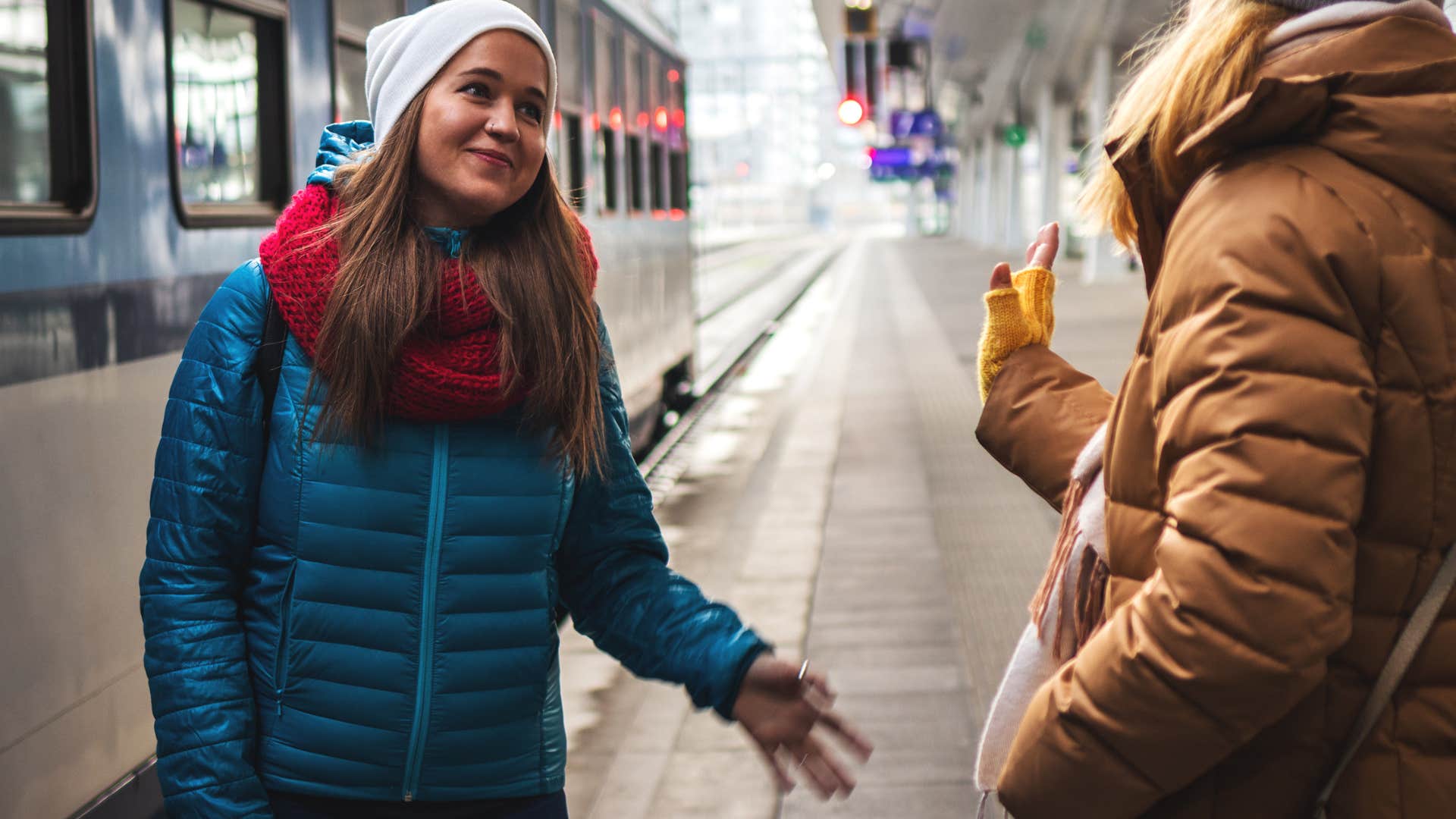 woman at the train station with friend telling her i'm heading out
