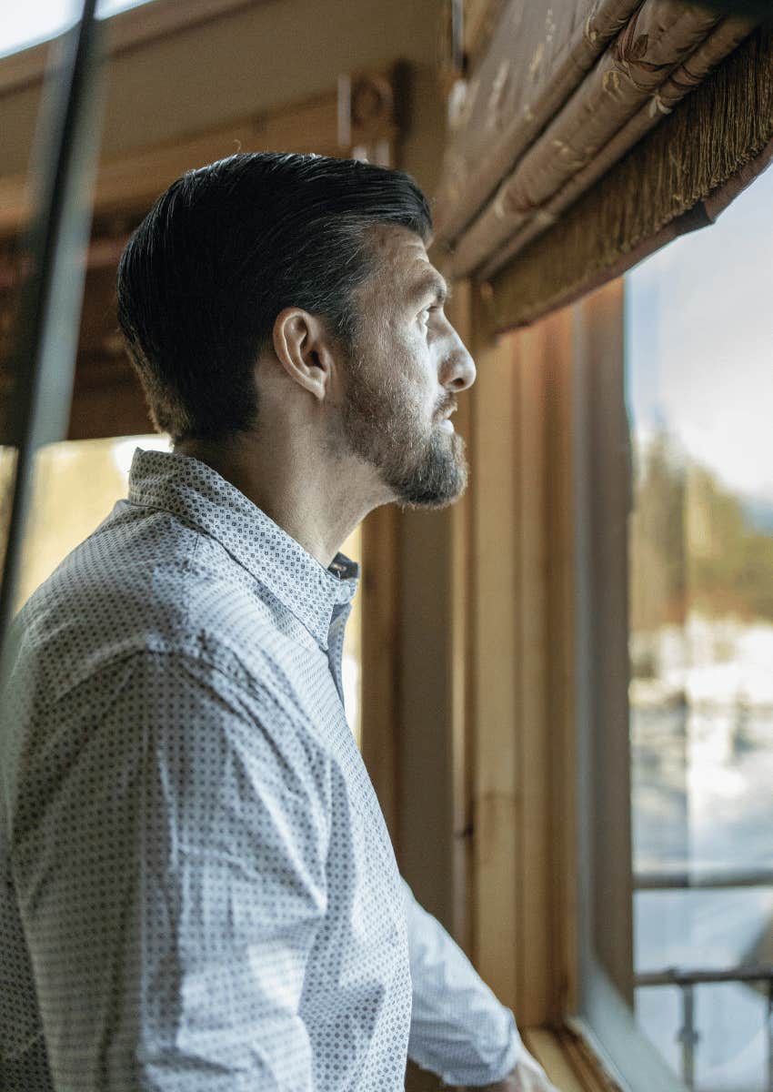 professional man staring out of window with an empty gaze