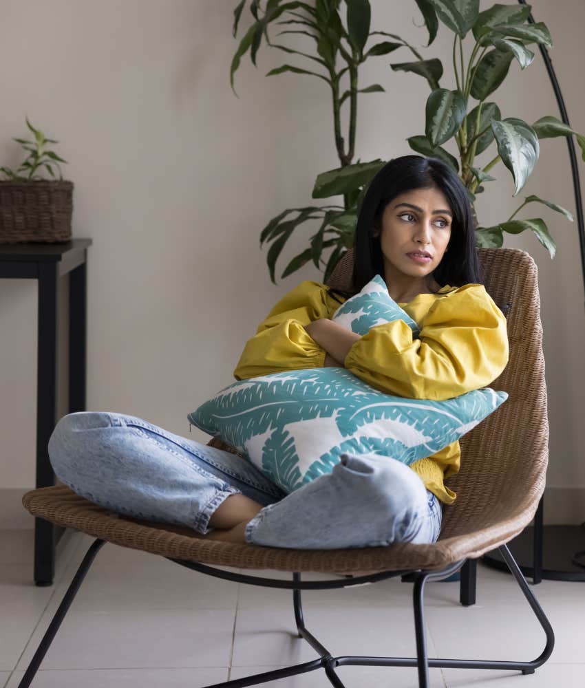 anxious person in chair hugs pillow showing struggle to cope