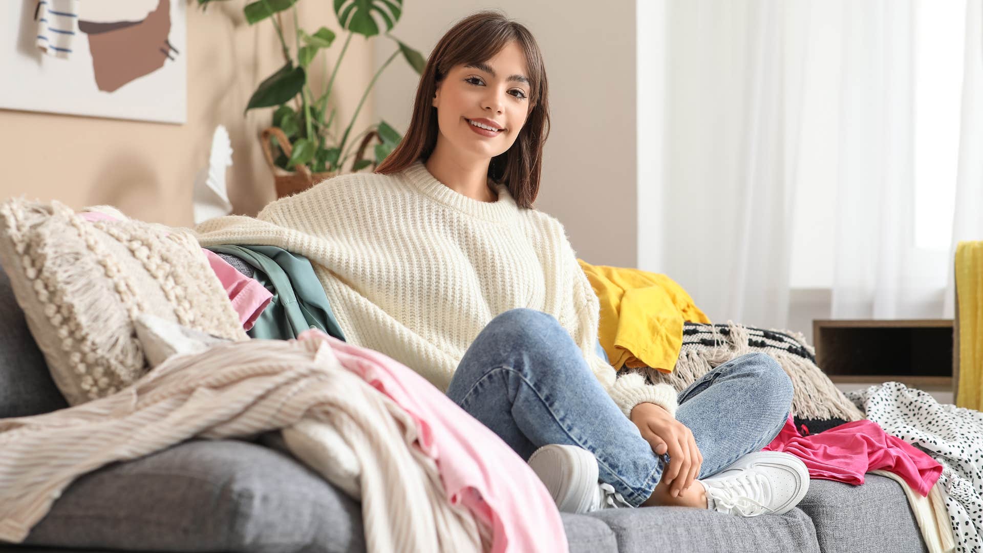 woman feeling calm sitting among clutter and clothing 