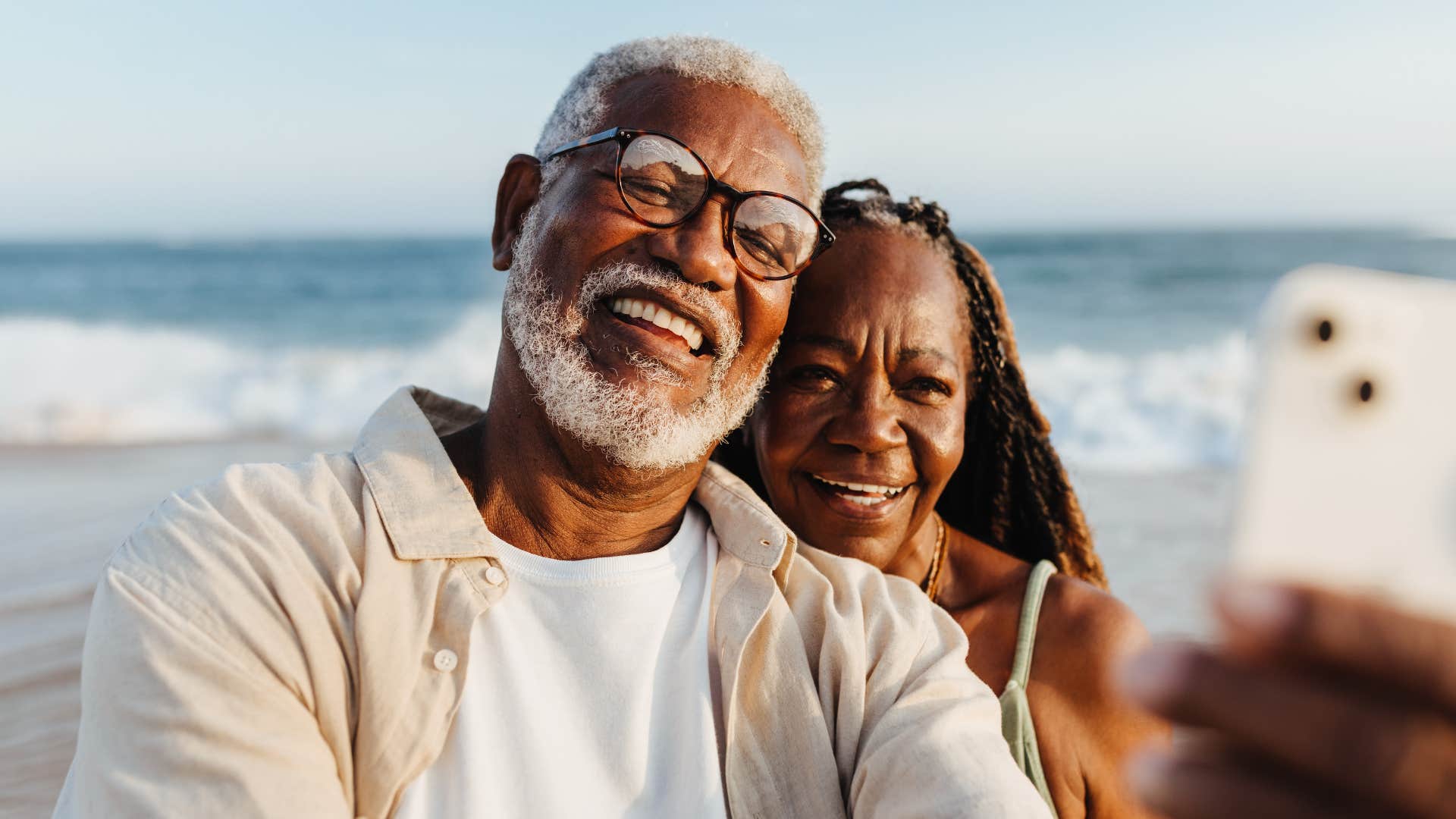 Happy older couple planning for retirement and smiling at the beach