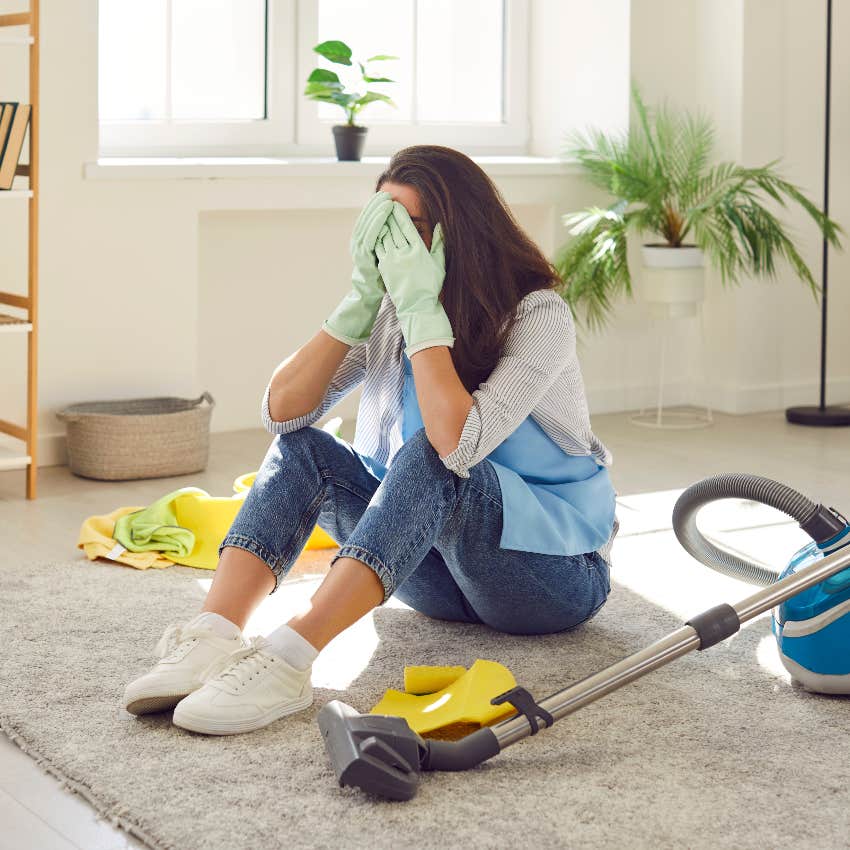 woman sitting on floor while cleaning with head in hands
