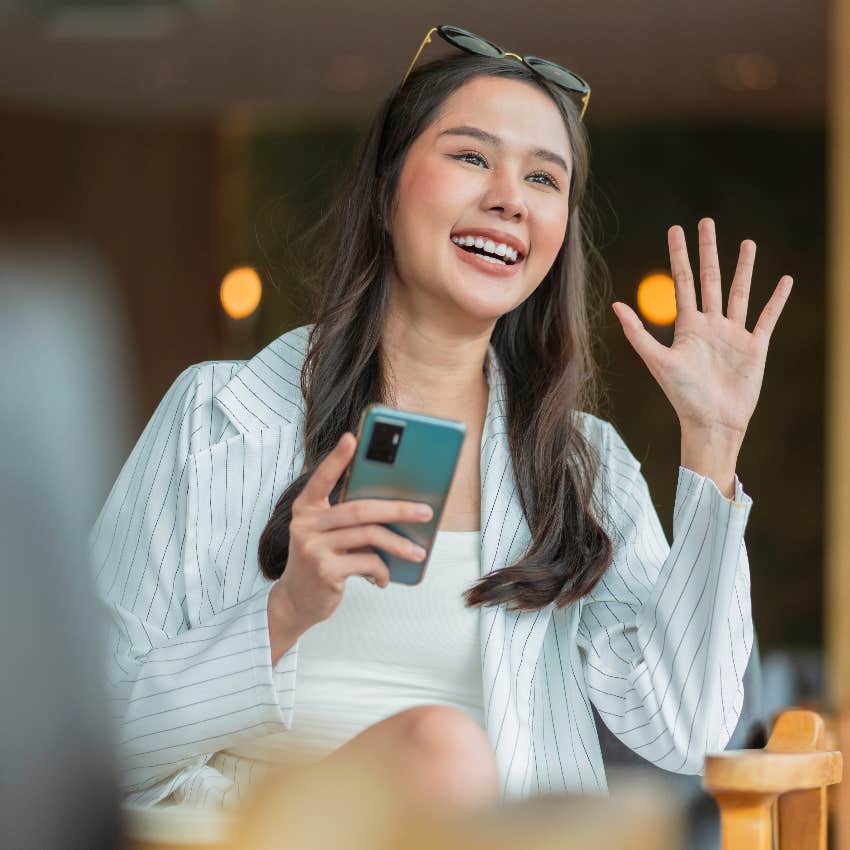 type a woman waving from chair holding cellphone