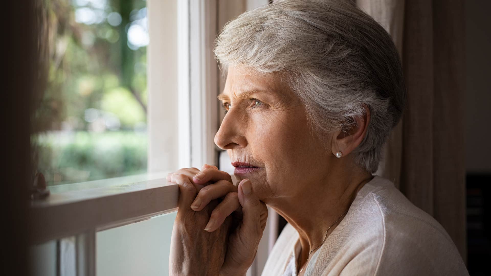 Woman who seems lonelier than usual looking out her window.