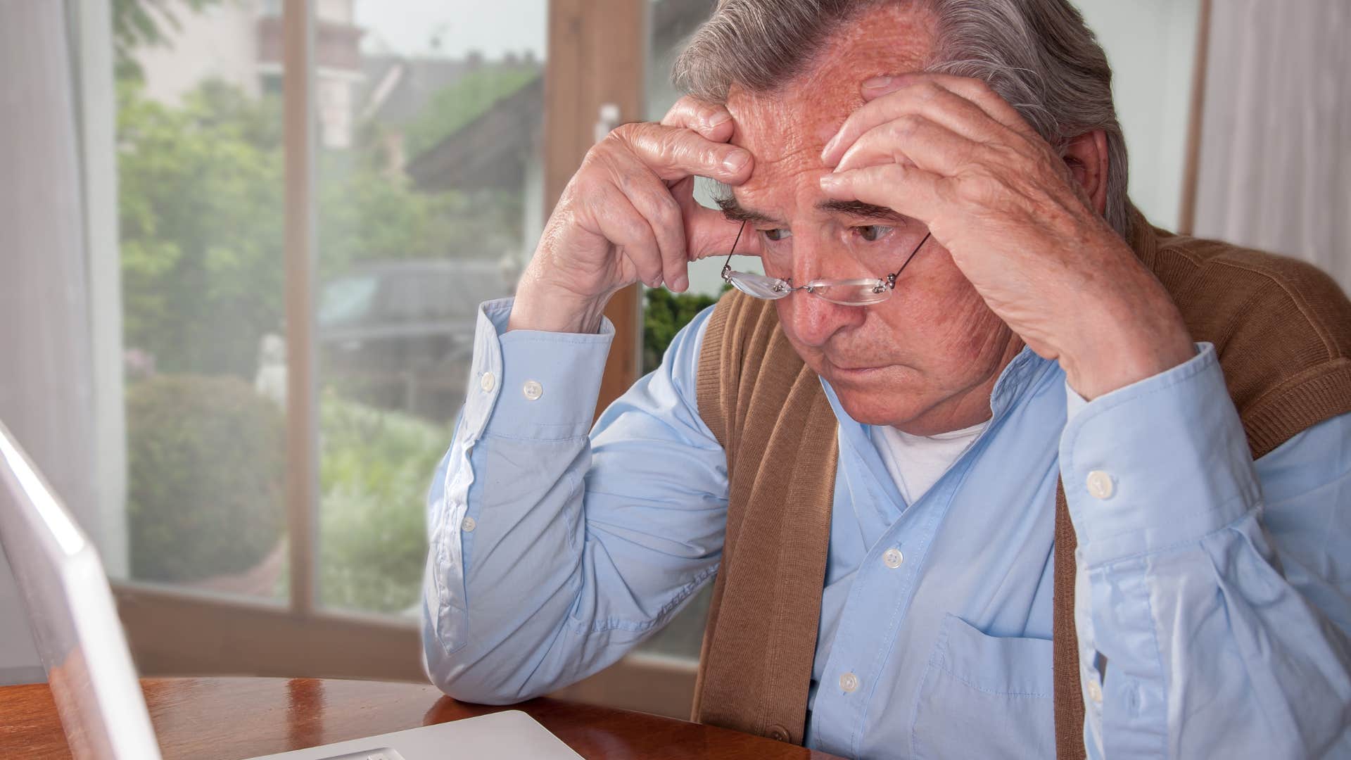 Man overwhelmed by basic daily tasks looking at his computer.