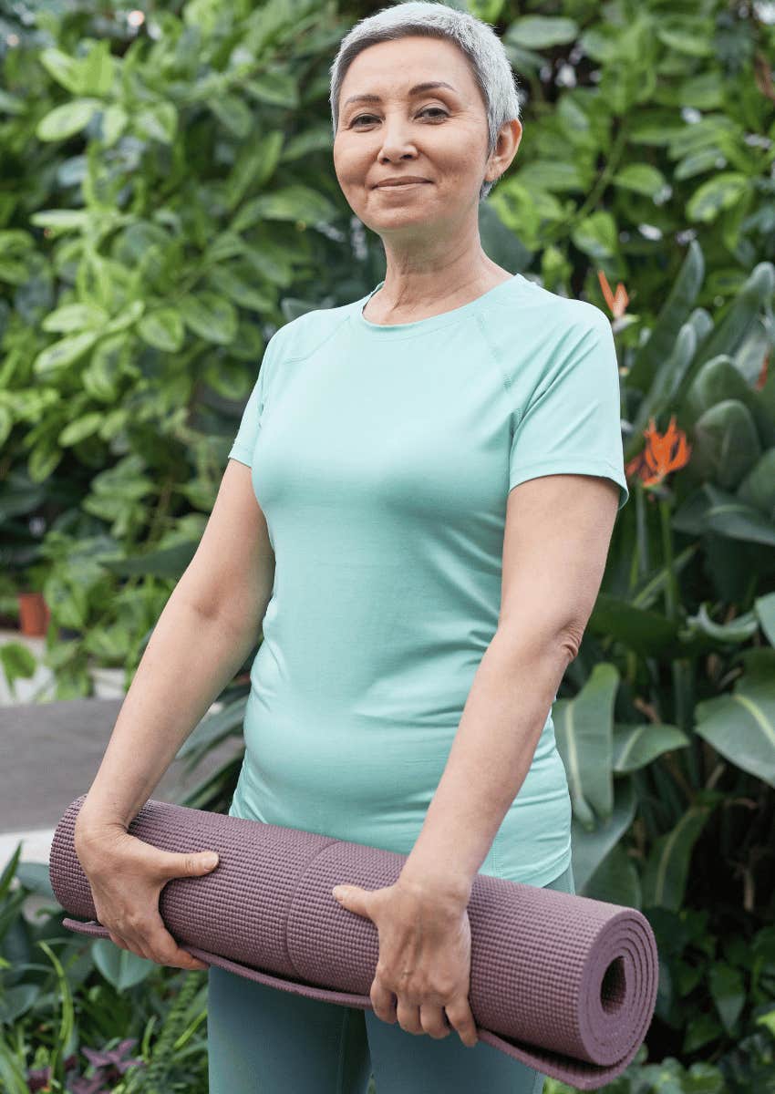 smiling older woman holding yoga mat
