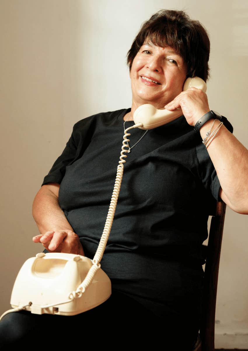 smiling older woman talking on landline phone