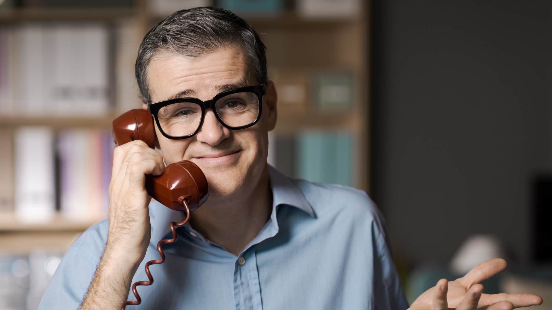 man in blue shirt on phone as he shrugs and says that's just how i am