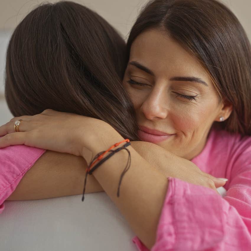 woman comforting and hugging friend pretending she's okay